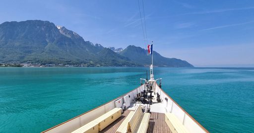 A beautiful view of a clear sea and mountains from a boat with the flag of France