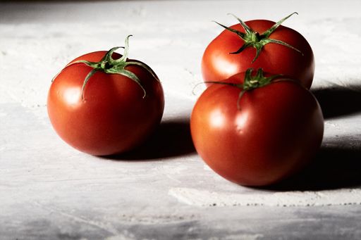 A closeup shot of three fresh tomatoes on a wooden surface