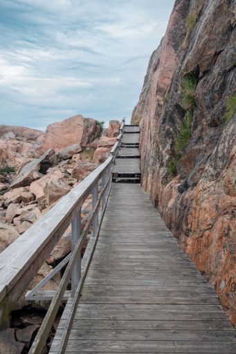 A vertical shot of the wooden stairs for climbing a rocky mountain in Sweden