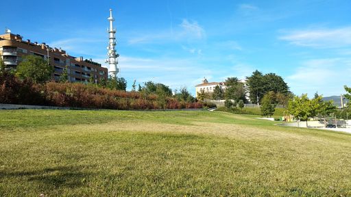 A tall white TV tower seem from a green park