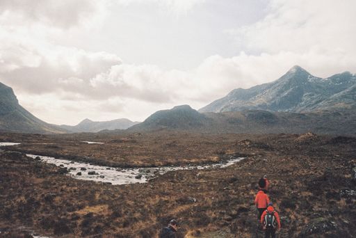 Hikers going through a beautiful field with an amazing sky and high snowy mountains in the background