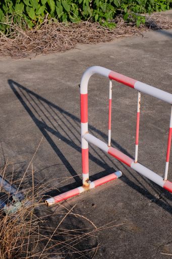A vertical shot of a steel road barricades on a narrow road in a rural area during daylight