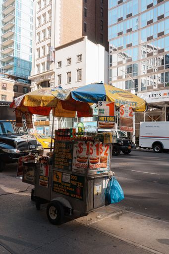 A vendor cart with umbrellas in New York City selling sausages