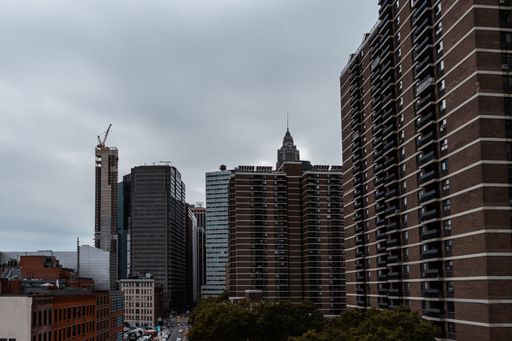 A scenic aerial view of a bustling metropolitan cityscape, featuring residential apartment complexes, tall skyscrapers, and dense foliage of trees