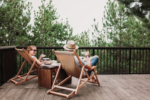 A lovely couple chilling  and having a cup of coffee on sunbeds in a balcony