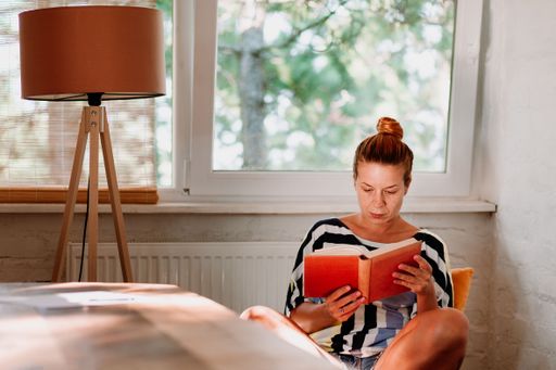 A Caucasian female reading book at home