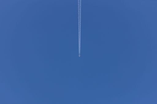 A low angle shot of a blue sky view with traces of the plane