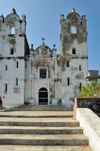 A vertical shot of stairs leading to an old Portuguese Church against a blue sky on a sunny day