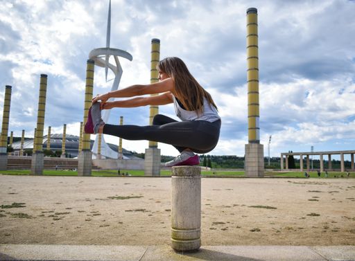 A shallow focus of a female doing yoga in a park under the sunlight and a cloudy sky