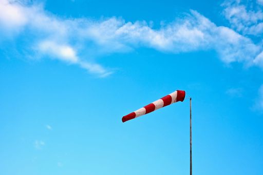 A low angle shot of a red white windsock in a blue sky