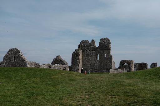 A horizontal shot of historical building ruins in the field under the clear blue sky