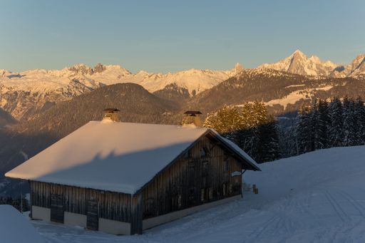 A wood cabin hut on a snowy surface with Mont Blanc mountain range in the back
