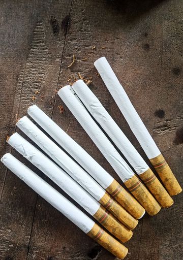A top view shot of several cigarettes on a wooden table