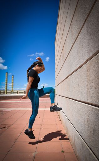 A shallow focus of a female in sportswear exercising in a park under the sunlight