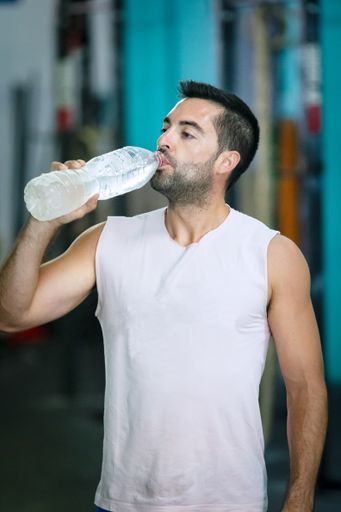 A shallow focus shot of a young male drinking water from a bottle