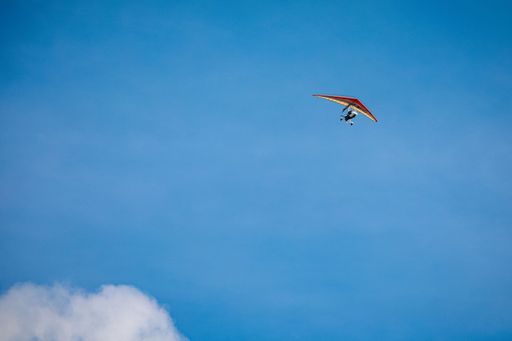 A view of hang glider flying high in the blue sky