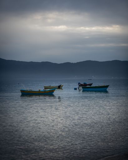 A vertical shot of empty boats anchored in the sea near the shore on a rainy day