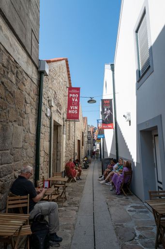 People enjoying their time in cafes on a narrow alley in Vila Nova de Gaia, Portugal, vertical shot