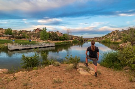 A scenic view of a male seen from behind, standing proudly on a bank of Fain Lake in Prescott Valley, Arizona at sunset
