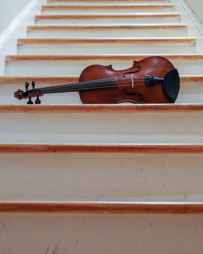 A vertical shot of a brown cello on the white stairs of atheater