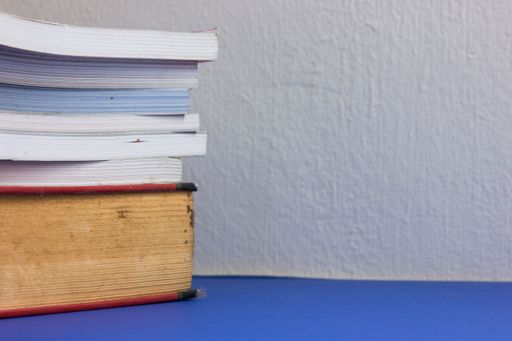 A stack of books on the blue table against a white wall background