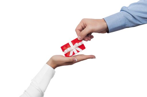 A closeup shot of a male hand giving a gift card to a female hand on a white background