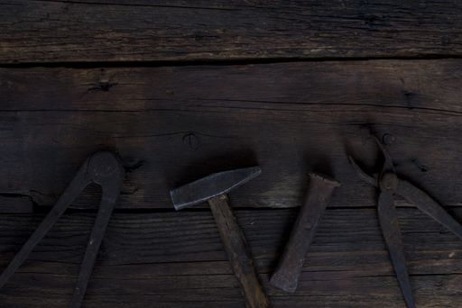 A top view of rusty old tools on a dark wooden background