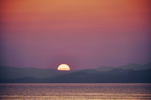 A beautiful shot of the sea with the sun going down behind the mountains at sunset