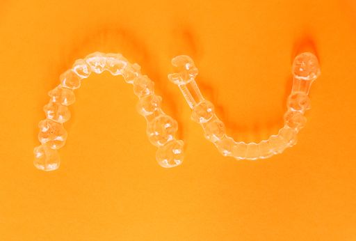 A top view of transparent aligners isolated on an orange background