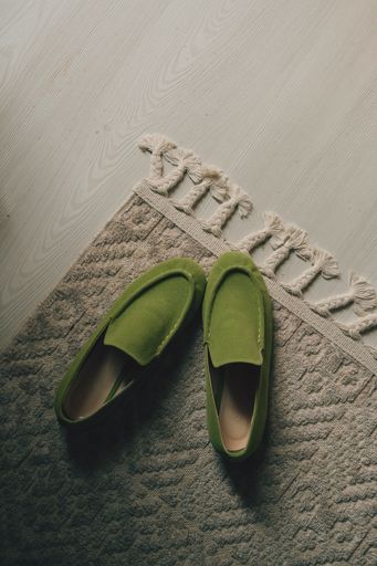 A vertical top view of a pair of green loafers on the rug