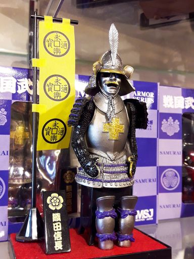 A miniature model of Japanese warlord Oda Nobunaga whit military flag.Small iron armor statue, Nagahama, Shiga, Japan