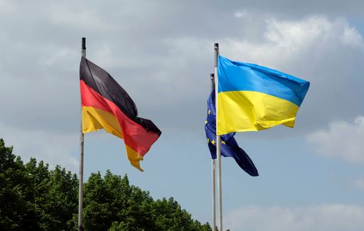 The flags of Ukraine, Germany, and the EU waving against the sky
