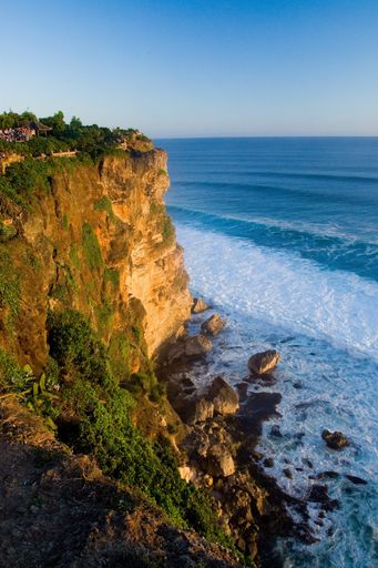 A vertical shot of Ulu Watu Cliffs in Indonesia under a clear blue sky