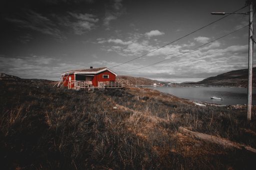 A scenic view of a small cabin in a rural area in cloudy sky background