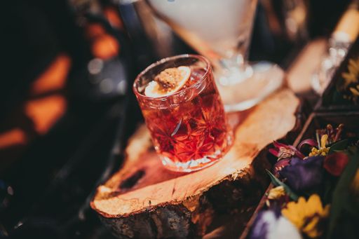 A close-up shot of a Negroni cocktail on a cross-section of a tree trunk.