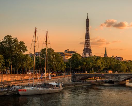A scenic view of a boat in the Seine river, with the iconic Eiffel Tower in the background at sunset