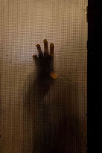 A vertical shot of a man's hand touching the brown glass door