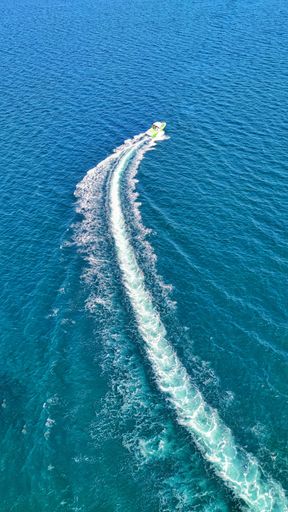 A vertical shot of a yacht driving in the sea and leaving traces.