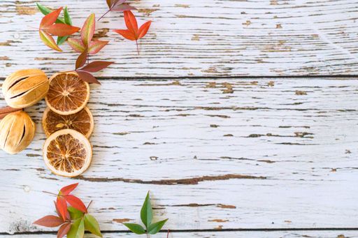 A top view of dried fruits and spices with colorful autumn leaves on a wooden surface with copy space