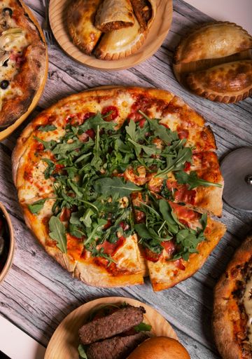 A vertical top view of a cheese pizza with aragula