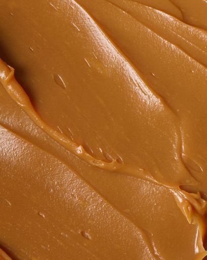A vertical closeup shot of a smooth creamy brown peanut butter surface