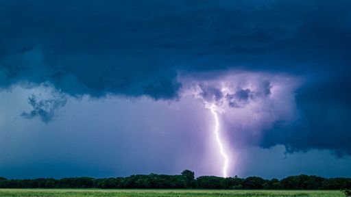 A beautiful shot of purple lightning striking on a field