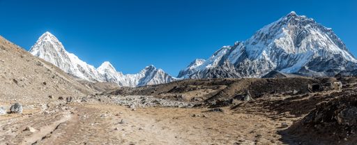 A panoramic shot of a beautiful valley surrounded by mountains with snowy peaks.