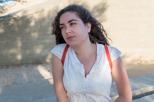 A young Caucasian woman sitting on a stone fence