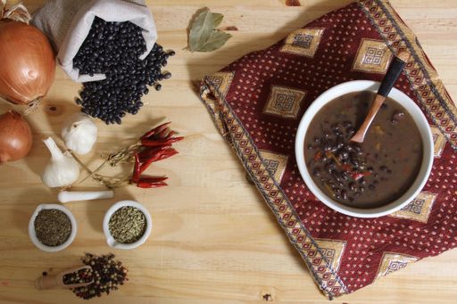 Herbs and Spices on Rustic Table With Black Beans in Background