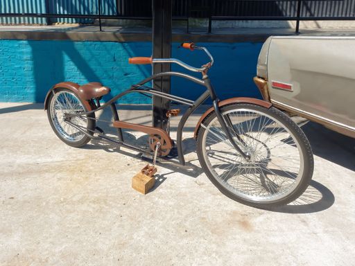 An old brown bicycle leaning on a metal pole