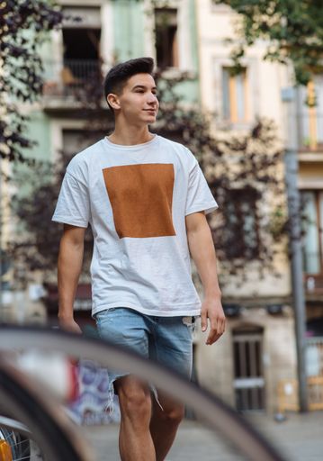 A young attractive man with white T-shirt and denim shorts walking down the street