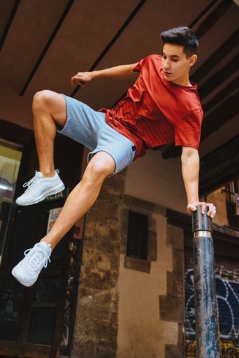 A young attractive man with casual outfit jumping leaned to a metallic stand