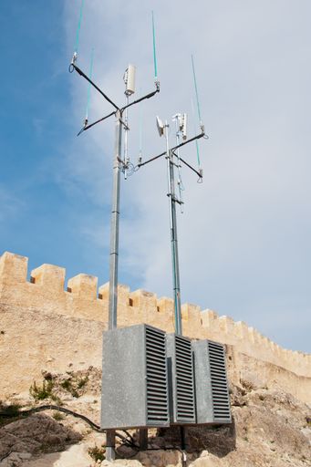 A vertical low angle shot of antennas under a cloudy sky