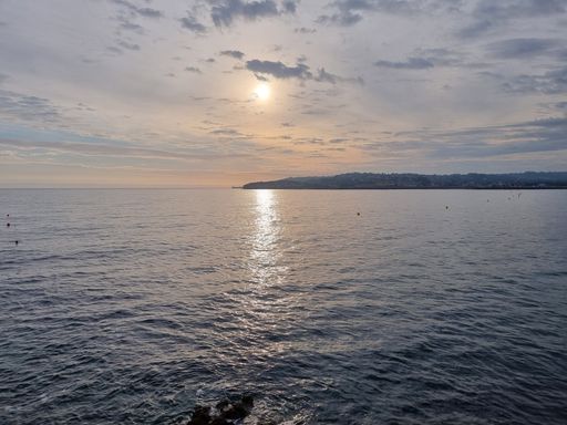 A scenic view of the tranquil water of a sea against Gijon at sunset in Spain